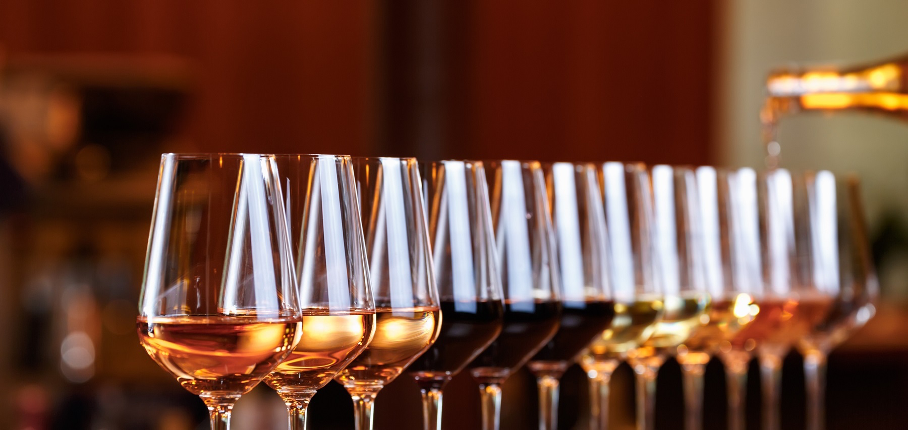 Wine glasses in a row. Pouring wine. Buffet table celebration of wine tasting. Nightlife, celebration and entertainment concept. Horizontal, wide screen banner format (Wine glasses in a row. Pouring wine. Buffet table celebration of wine tasting. Nigh